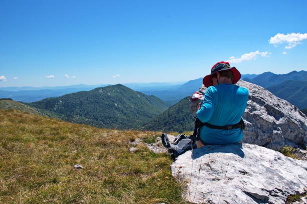 istock Senior woman sitting on mountain peak 1575682575