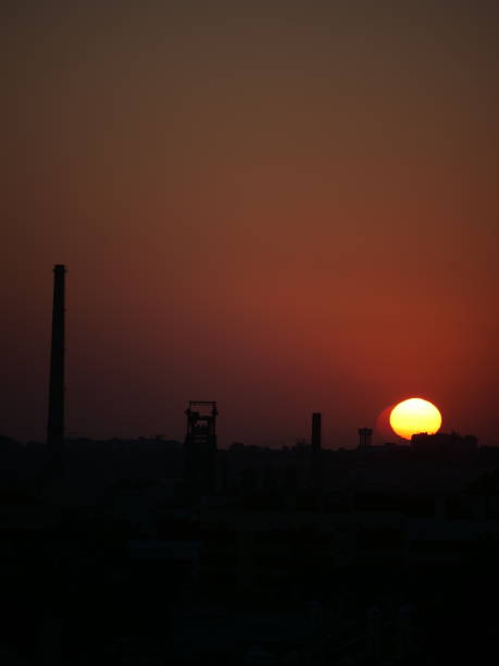 istock Morning sunrise, Bright orange sun on chimney silhouette 1575684255
