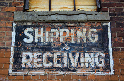 Shipping and receiving painted sign on brick wall of run down warehouse/ factory in downtown Detroit