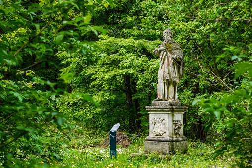 statue on a pedestal of a saint of a monastery in the forest