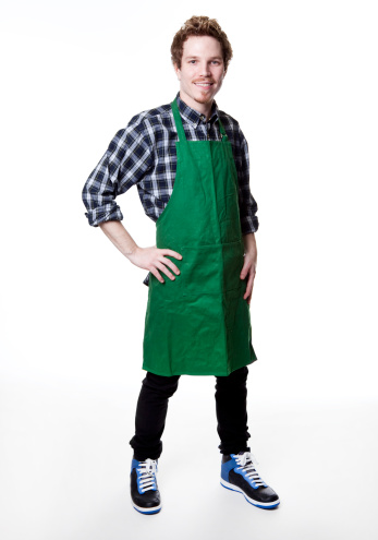 Man wearing an apron and holding a pair of scissors and a hair comb isolated on white background