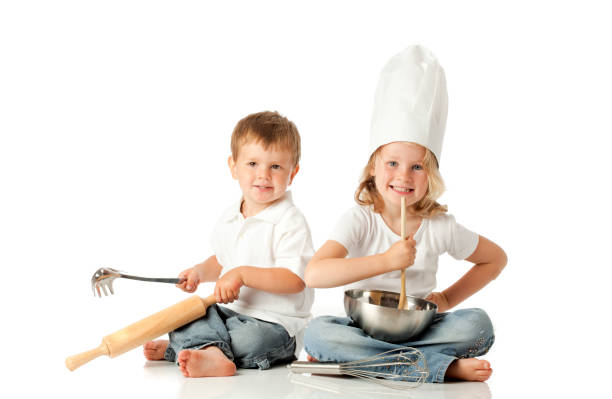 Kids having fun in the kitchen playing with kitchen utensils. Isolated on white.
