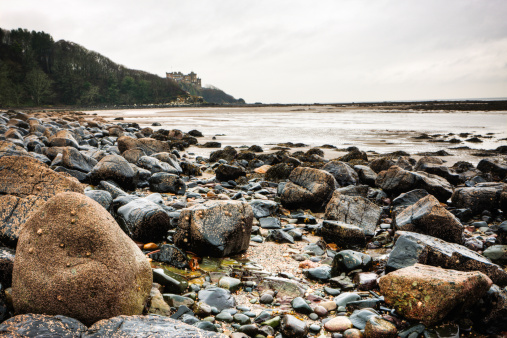 A rocky beach infront of Culzean Castle in Ayrshire, Scotland. Rocks in focus. HDR treatment. Edited as a 16 bit ProPhoto Tiff in Lightroom and Color Efex Pro. Velvia conversion for impact. Some grain.