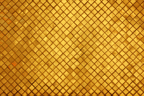 A mosaic of small gold tiles running diagonally across the image.  The location is a Thai Buddhist temple in Bangkok, Thailand.