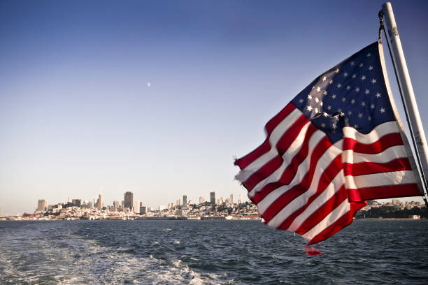 Shot taken on the ferry to Alcatraz island: the stars and stripes flag with the cityscape of San Francisco on the background (California, USA).