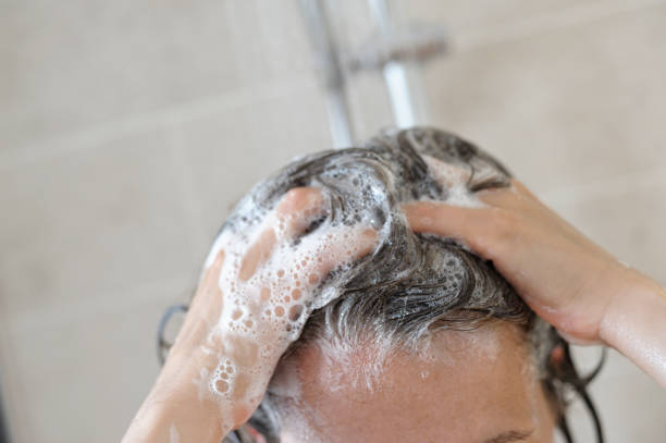 mujer limpieza su cabello en la ducha - desaturado fotografías e imágenes de stock