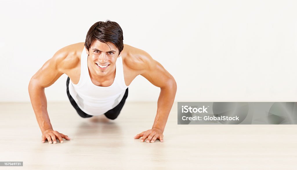Hombre feliz haciendo push ups fitness en el gimnasio - Foto de stock de 20-24 años libre de derechos