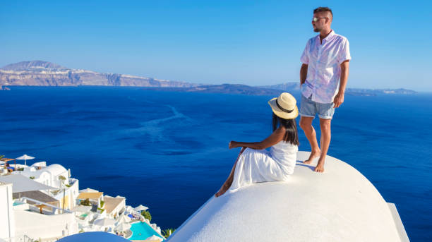 Couple on vacation in Santorini Greece, men and women at the streets of the Greek village of Oia Couple on vacation in Santorini Greece, men, and women on the streets of the Greek village of Oia Santorini happy couple on vacation in santorini greece stock pictures, royalty-free photos & images