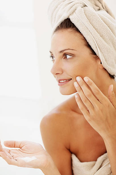 istock Woman applying moisturizer to her face after shower 157569776