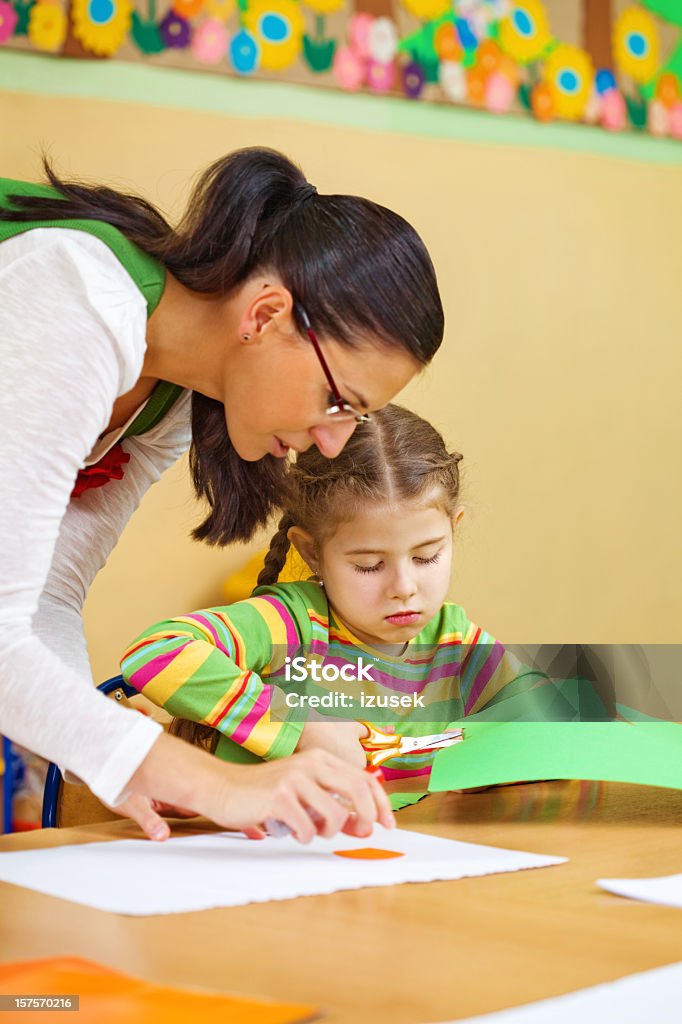 Professor ajudar uma menina com obras de arte - Foto de stock de Aluno de Primário royalty-free