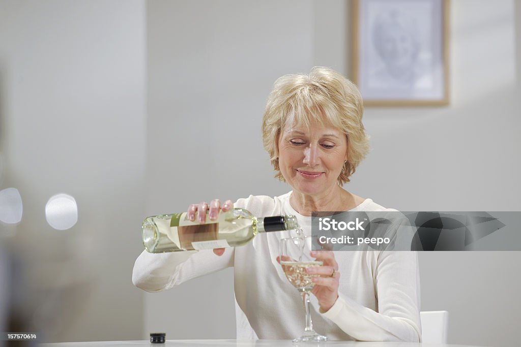 Schöne senior Frau gießen Weißwein in ganz wie zu Hause fühlen. - Lizenzfrei 60-69 Jahre Stock-Foto