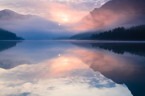 Beautiful reflection from the mountains, the forests and the clouds at Piburg lake in Austria