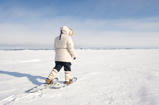 A woman walks on snowshoes across the frozen surface of Great Slave Lake in Canada's Northwest Territories.  Click to view similar images.