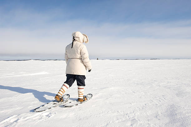 Arctic Snowshoeing, Yellowknife. A woman walks on snowshoes across the frozen surface of Great Slave Lake in Canada's Northwest Territories.  Click to view similar images. great slave lake stock pictures, royalty-free photos & images