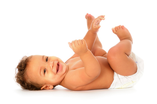 A baby lying on his back, smiling and looking at the camera against awhite background