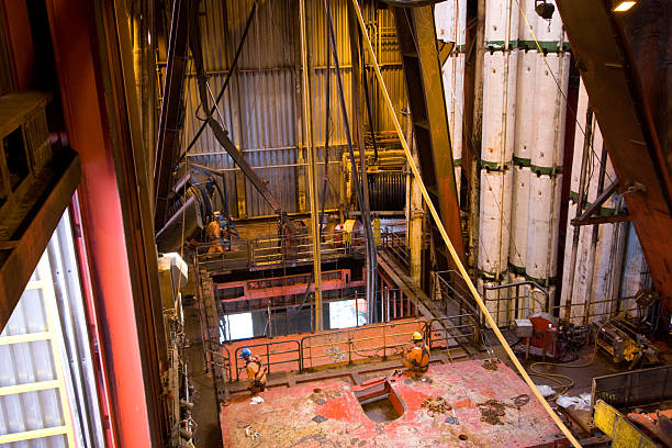 homme travaillant sur une plateforme pétrolière offshore moonpool riser vue - oil rig oil industry sea riser photos et images de collection