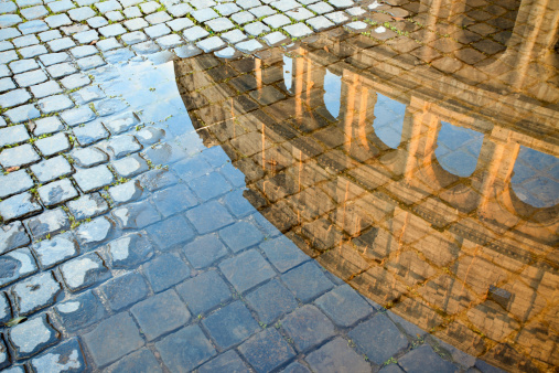 Coliseum reflected in a puddle and cobblestones. Roma Italy