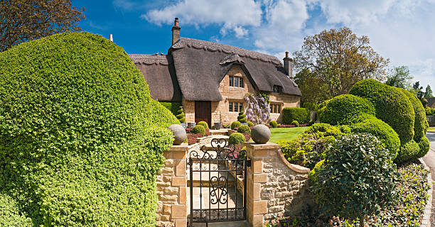 idyllic country cottage thatched roof pretty summer gardens cotswolds uk - huisje stockfoto's en -beelden