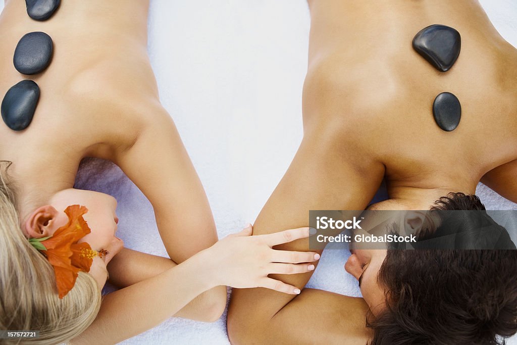 Casal relaxante durante uma terapia com pedras quentes no spa - Foto de stock de De Bruços royalty-free