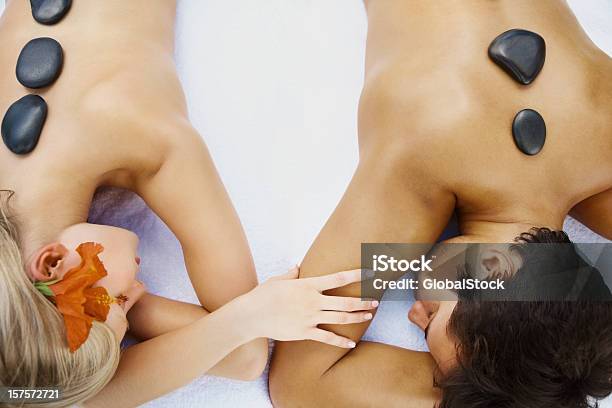 Foto de Casal Relaxante Durante Uma Terapia Com Pedras Quentes No Spa e mais fotos de stock de De Bruços