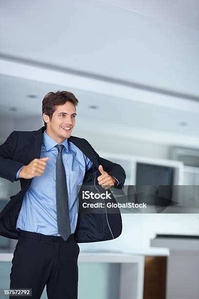 Young Business Man Putting En Su Abrigo Foto de stock y más banco de imágenes de Vestirse - Vestirse, Traje, Hombres
