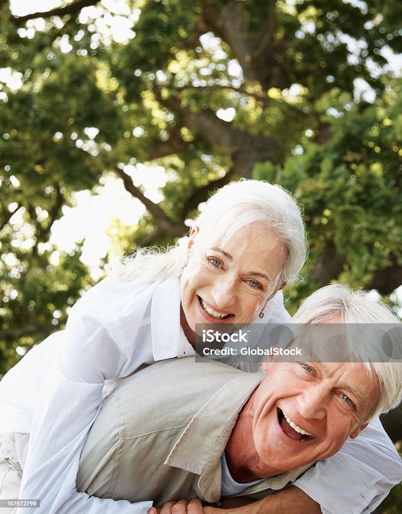 Glücklich Älterer Mann zu seiner Frau geben Huckepack nehmen - Lizenzfrei 55-59 Jahre Stock-Foto