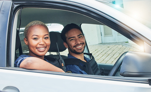 Police, driving together and portrait in car, smile and happy partnership to stop crime with teamwork in city. Black woman, man and patrol street in metro for justice, law and government surveillance