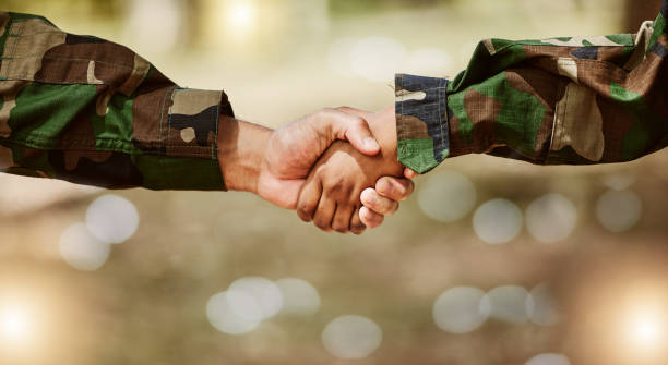 istock Army, camouflage and handshake for peace deal, problem solving and support for world solidarity. Partnership, connection and military people shaking hands in trust, agreement or mission cooperation. 1575735240