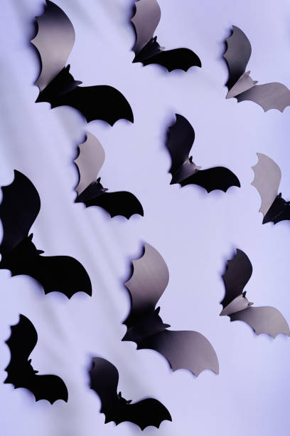 istock Minimal flat lay with black bats and shadow as halloween party background. Pattern from decorative fly bats on lavender colored background, aesthetic screensaver. Halloween holiday concept 1575737886
