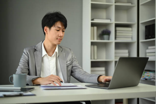 istock Millennial businessman wearing formal wear working with statistical document in modern office. 1575749174