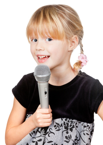 Cute little girl singing holding microphone on white background