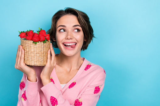 Photo of cheerful pretty girl stylish clothes presenting red delicious seasonal berries look empty space isolated on blue color background.