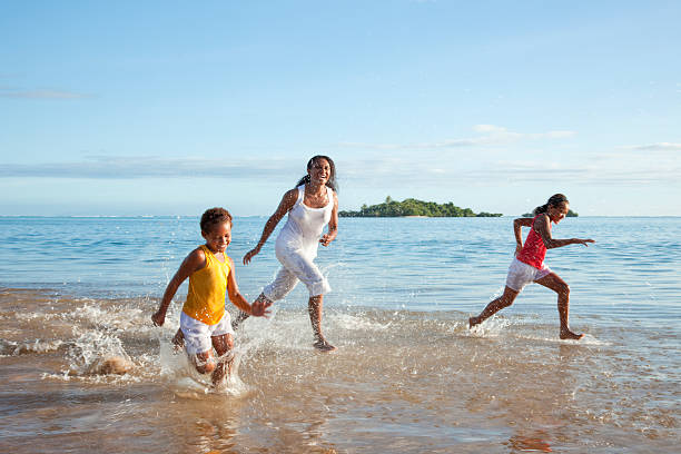 fiyiano madre e hijas corriendo en la playa - melanesia fotografías e imágenes de stock
