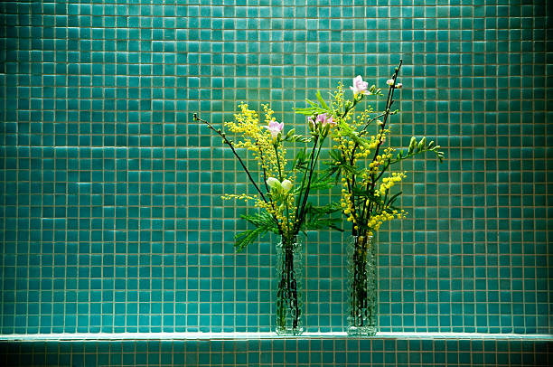 retro styled decoration with two flower bouquets in glass vase standing in front of petrol green colored glass tiles