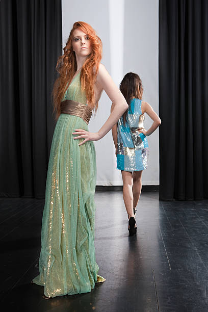 A fashionable woman showcases her beautiful dress with dramatic flair and poise in a modern setting.