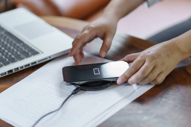 istock Charging mobile phone battery with wireless charging device in the table. Smartphone charging on a charging pad. Mobile phone near wireless charger Modern lifestyle technology concept 1575804402