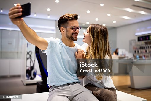 istock Smiling young couple looking at smartphone. Multiethnic people sharing social media on cell phone. 1575804963