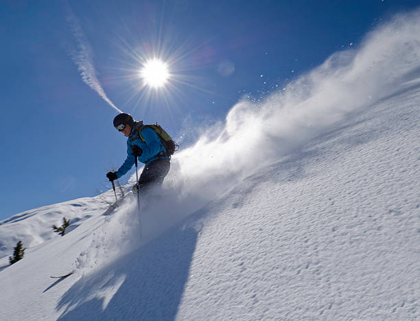 istock Man skiing down slope with blue sky and sun background 157580714