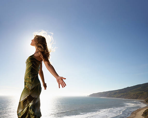 mujer de pie por el mar con brazos estirados - spaciousness fotografías e imágenes de stock