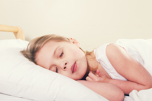 a little girl sleeping in bed.