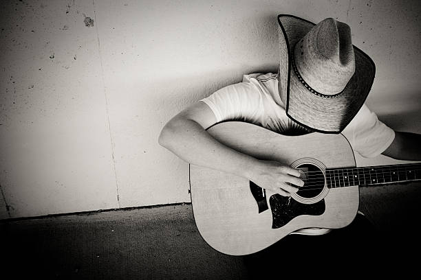 Cowboy playing Guitar Cowboy playing the guitar. Black and white image with contrast added. country and western stock pictures, royalty-free photos & images