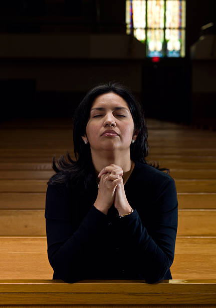 hispanic frau beten in der kirche - kneeling praying women begging stock-fotos und bilder