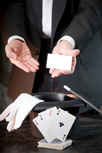 A performing magician produces a business card from his magic hat.