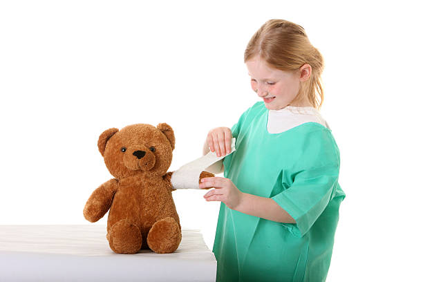 niña como el personal de enfermería que con una venda de peluche - child physical injury teddy bear wound fotografías e imágenes de stock