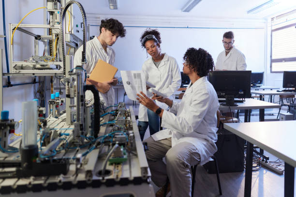 istock Group of young scientists talking about plans in robotics lab. 1575821039