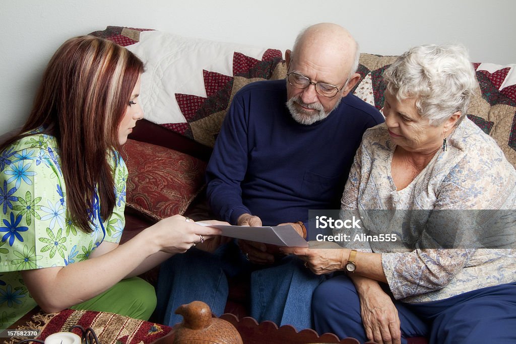 Casal Idoso olhando para livros com jovem enfermeira em Uniforme Hospitalar - Royalty-free Casal Idoso Foto de stock