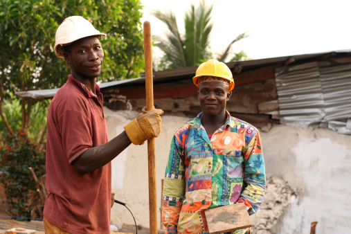Two men from Liberia, West Africa, mixing cement for the foundation of the small house they are building.