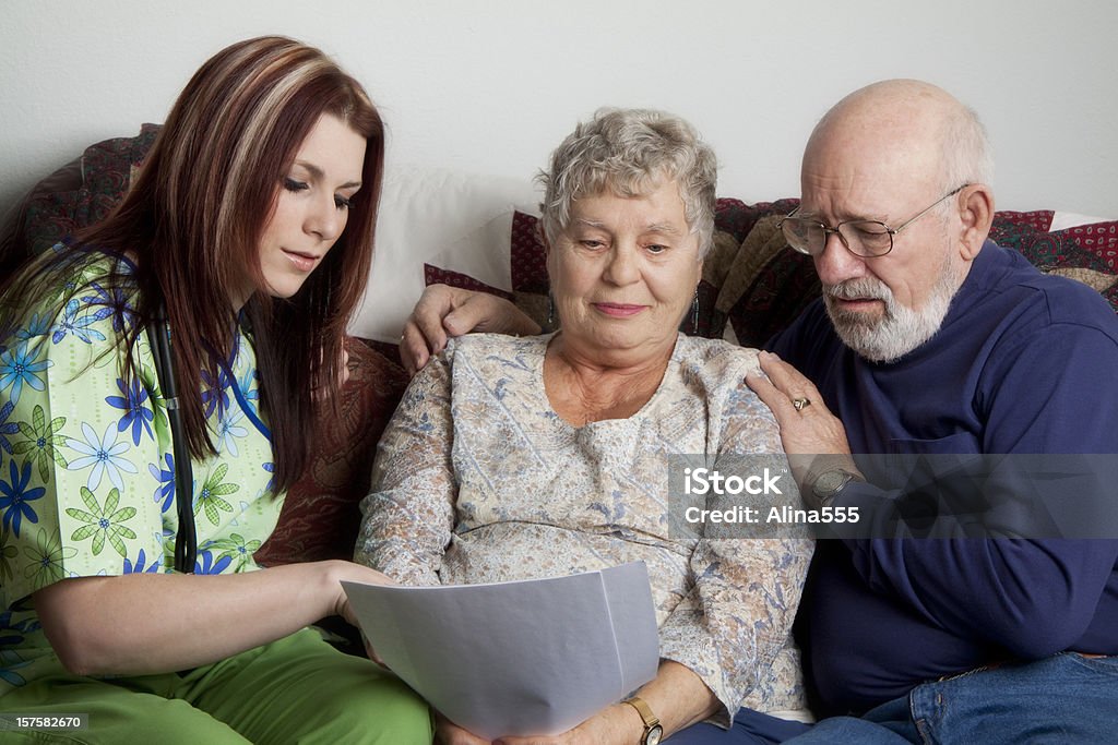 Пожилая пара, глядя на документы и молодая медсестра в Медицинская одежда - Стоковые фото Бумага роялти-фри