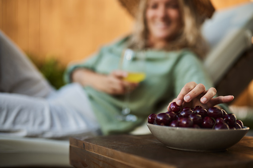 Close up of a woman eating fresh cherries while relaxing on a lounge chair.