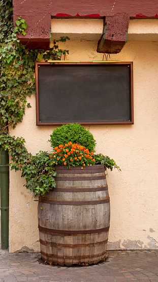 Decorative wine barrel and blank blackboard in front of a romantic restaurant in an old half-timbered house.  Wood framed empty menu board. You can add your own text.  Vertical orientation.  A DSLR-image with the dimensions of 1728 px × 3070 px